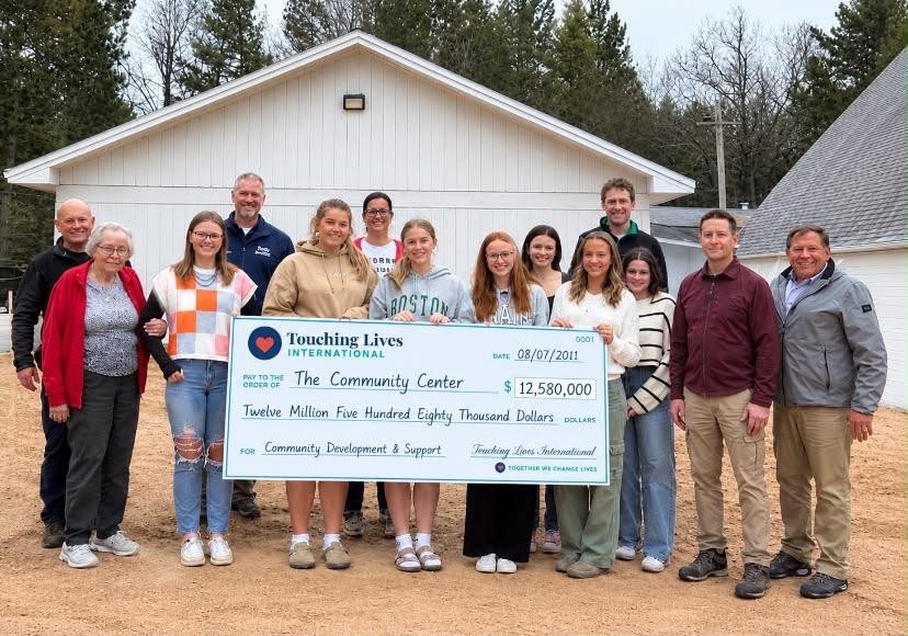 Group gathered outdoors with a presentation cheque